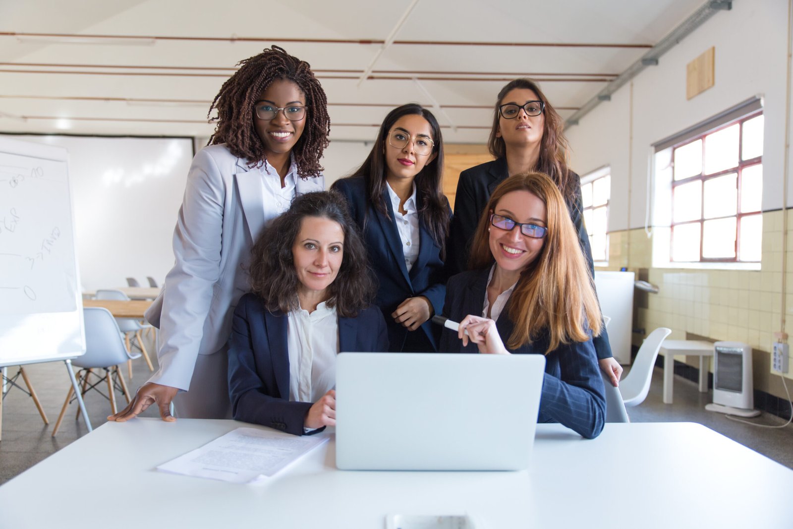 businesswomen using laptop and smiling at camera